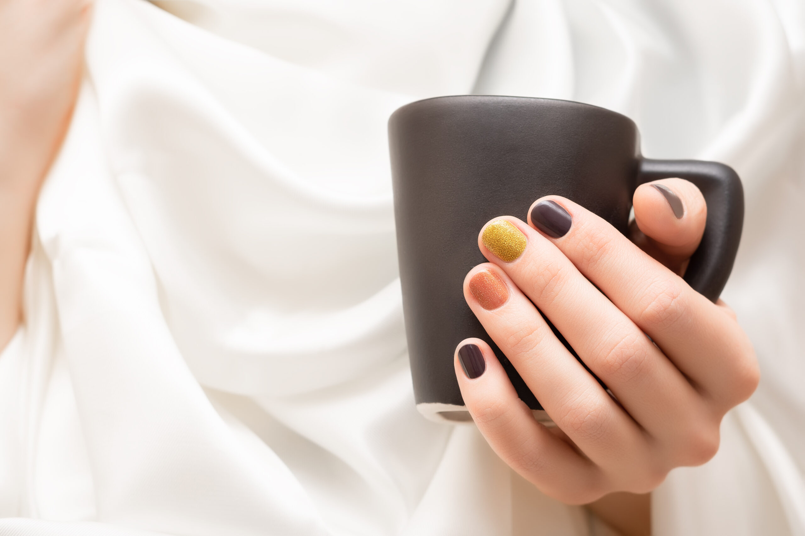 Female Hand With Brown Nail Design Holding Black Cup Scaled